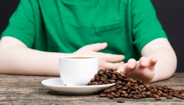 Enfants tenant touchant des grains de café versés sur une soucoupe et une tasse de café