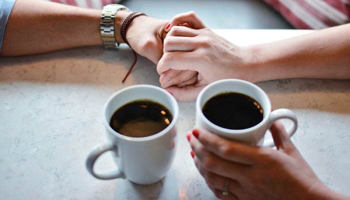 Deux personnes qui boivent un café et serrent les mains